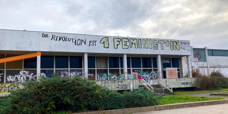 Schriftzug auf einem Gebäude: "Die Revolution ist 1 Feminist:in"