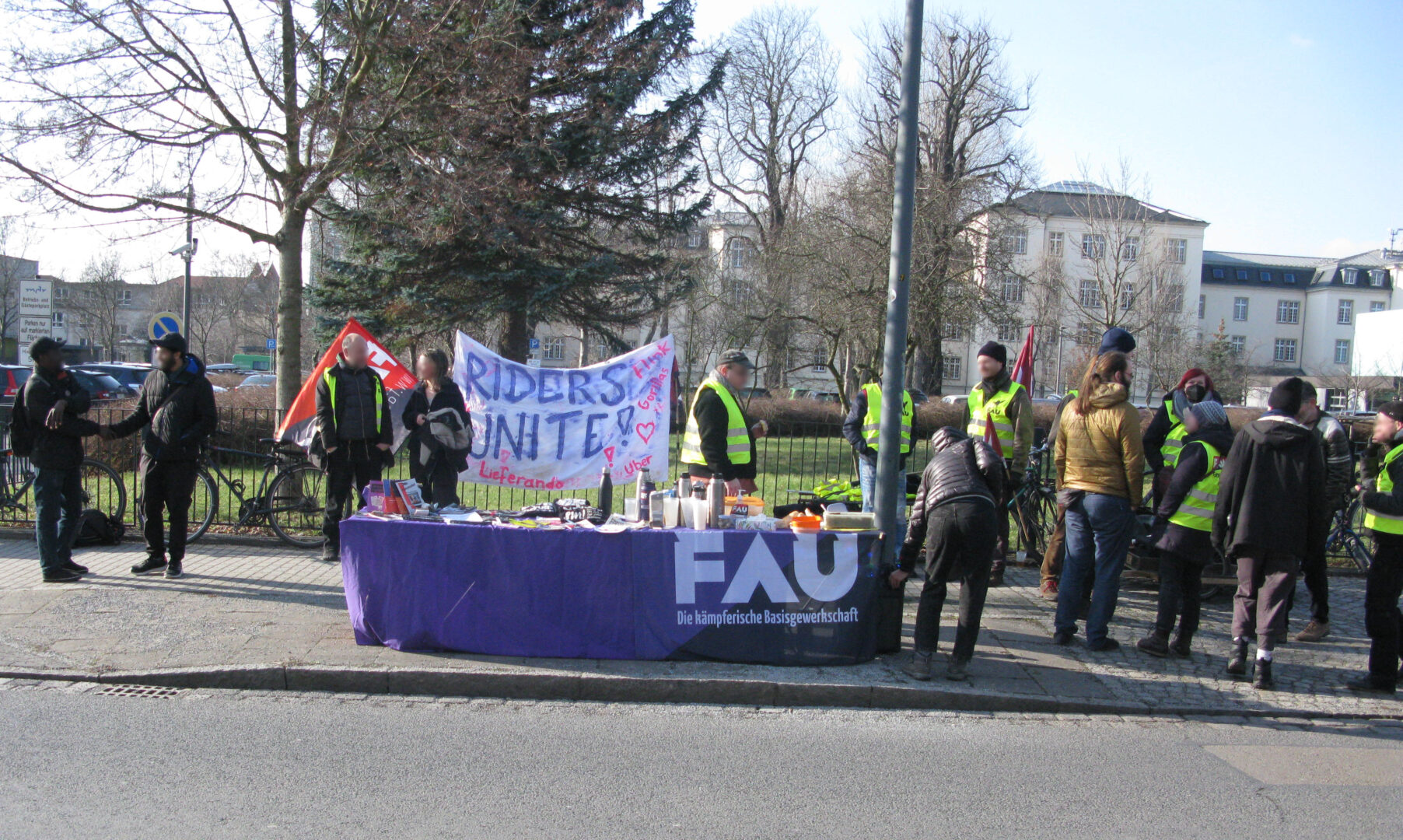 Etwa ein Dutzend Personen, viele mit FAU-Warnweste, stehen mit einem Info-Tisch auf dem Gehweg gegenüber des Arbeitsgerichts in Dresden auf der Hans-Oster-Straße.