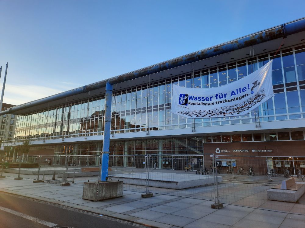 Banner vor dem Kulturpalast mit der Aufschrift "Wasser für alle - Kapitalismus trocken legen"